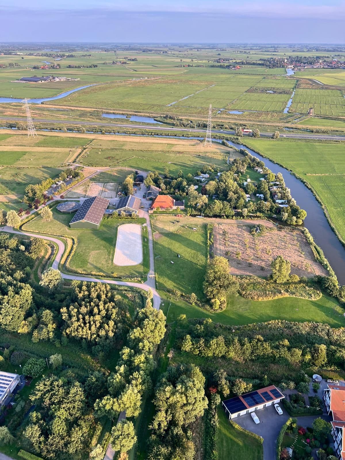Luchtfoto van Hiddema State: de boerderij en de bomen op de terp, met daaromheen weilanden en een vaart.